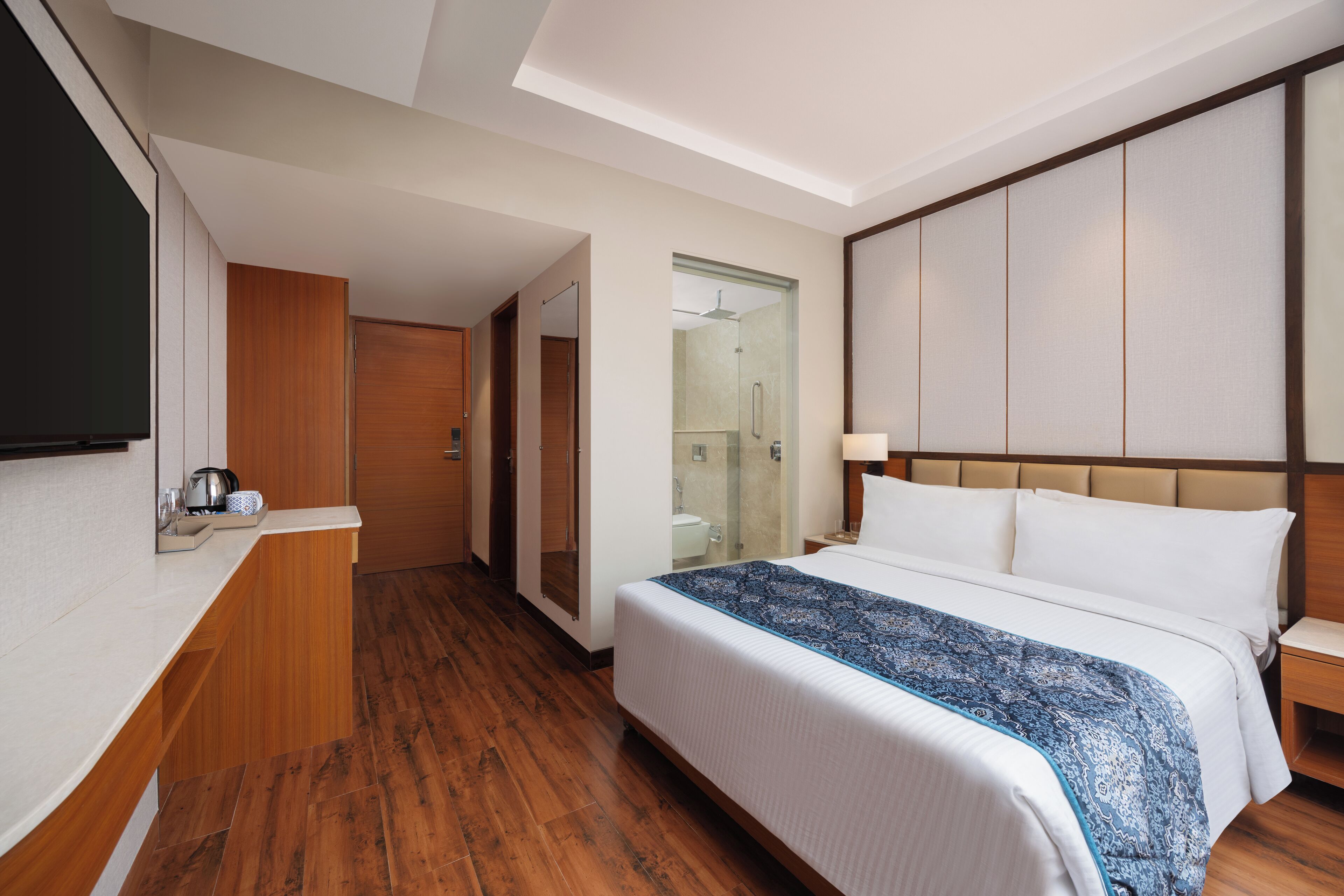 Una habitación de hotel con una cama, una mesita de noche y un televisor a la izquierda.