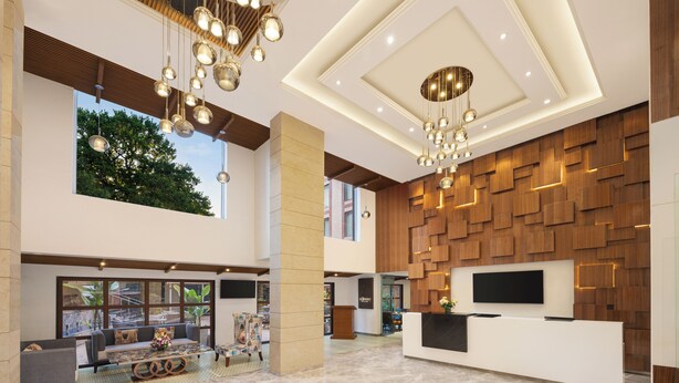Eine geräumige Lobby mit einer Rezeption, einer Sitzecke und einem großen Fenster mit Blick auf Grünflächen.