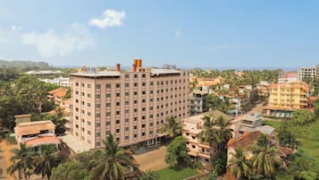 A multi-story hotel with a central courtyard, surrounded by palm trees and other buildings.
