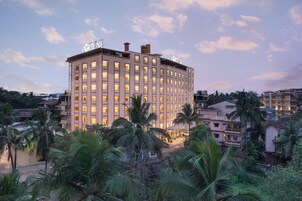 Un hotel de varios pisos con un patio central, rodeado de palmeras y otra vegetación.