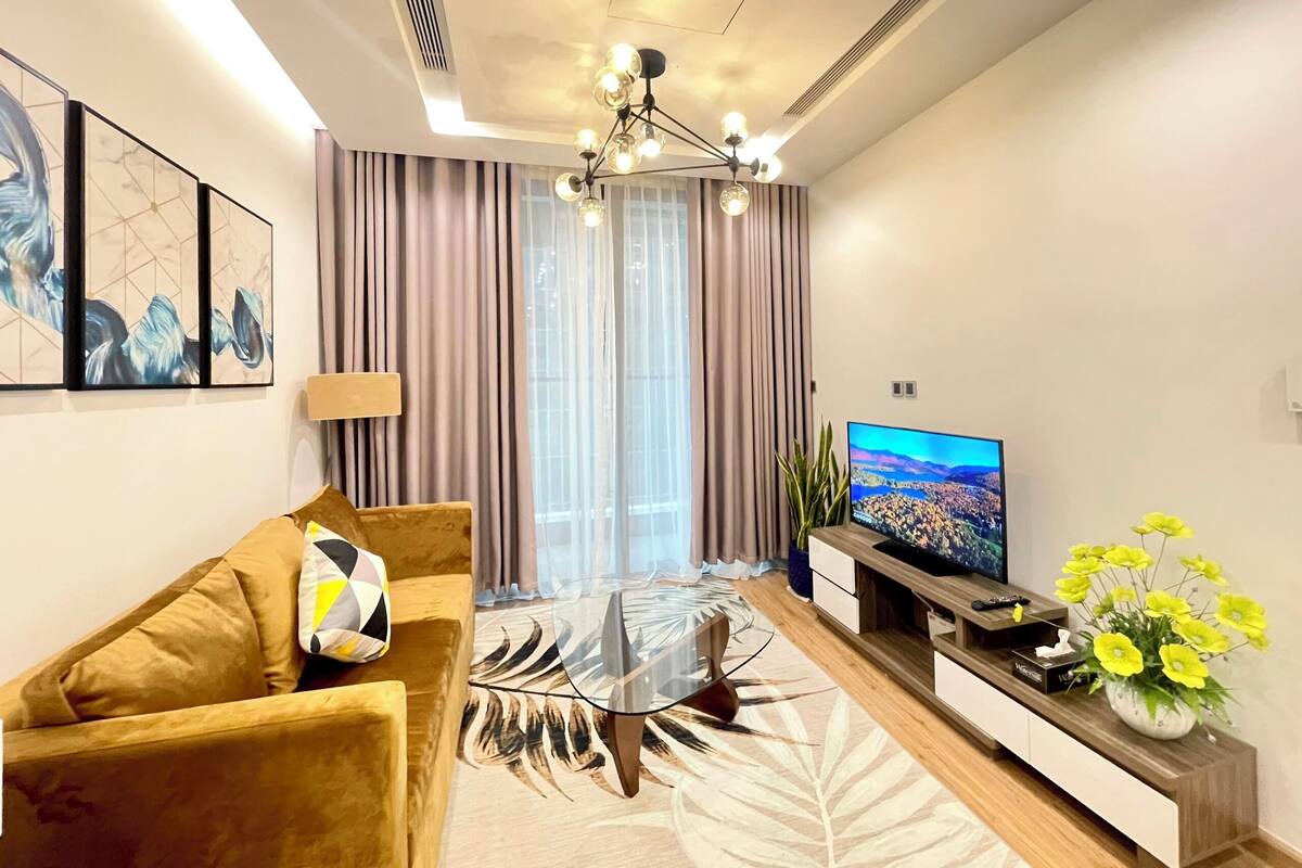 A modern living room with a sofa, coffee table, TV, and decorative plants.