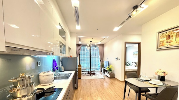 Una cocina moderna con electrodomésticos de acero inoxidable, una zona de comedor con mesa y sillas, y vistas a través de un amplio ventanal.