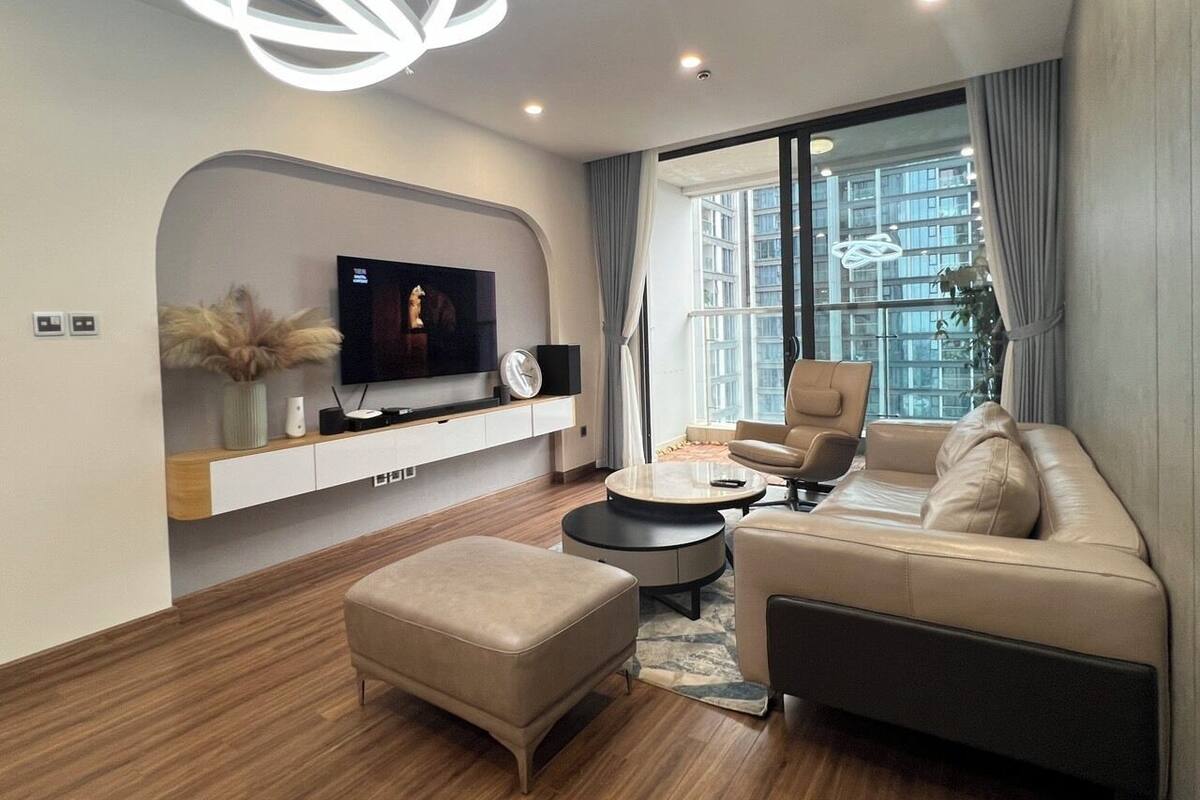 A modern living room with a flat-screen TV, a sofa, a coffee table, and a pendant light.