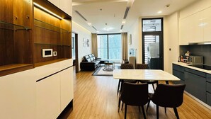 Una cocina moderna con armarios de madera, un comedor con mesa y sillas, y vistas a la ciudad a través de amplios ventanales.