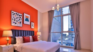 Ein modernes Schlafzimmer mit einem großen Bett, zwei Nachttischen und Blick auf eine Stadtlandschaft durch ein großes Fenster.