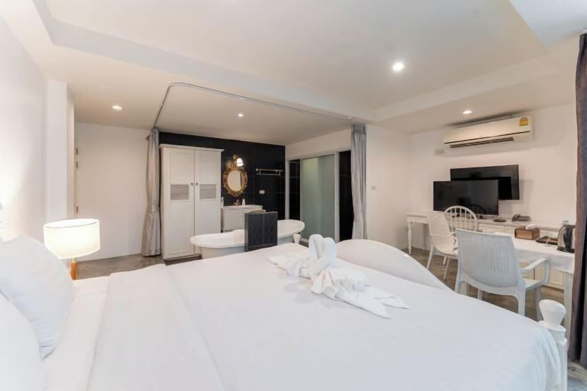 Una habitación de hotel con cama, escritorio, silla, televisor y baño.