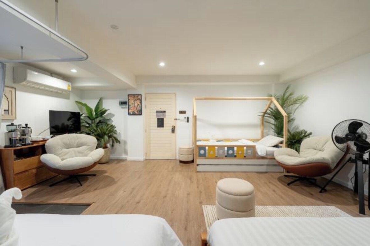 Ett modernt hotellrum med en säng, två fåtöljer, ett skrivbord, en TV och en balkong med utsikt.