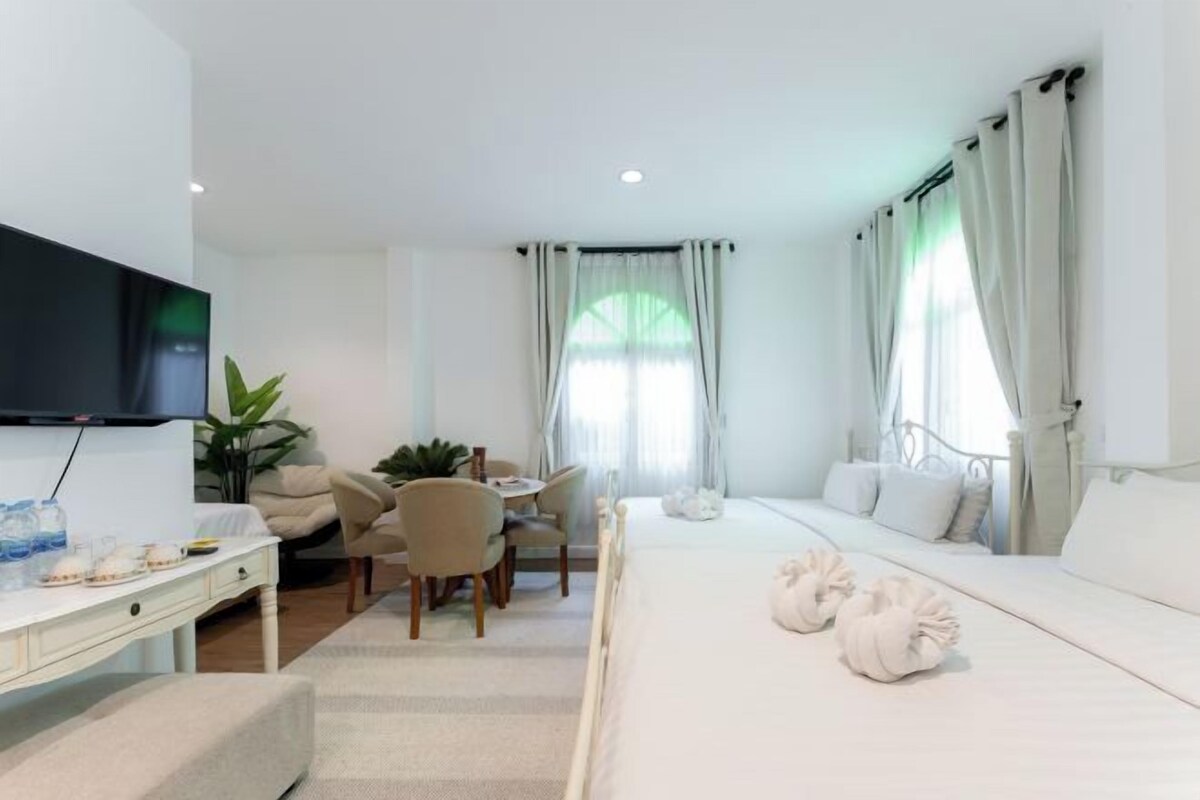 A hotel room with a bed, a desk, a TV, and a dining area.