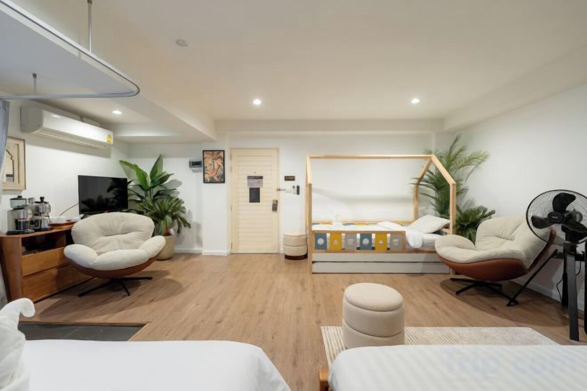 Una habitación de hotel moderna con una cama, dos sillas, un escritorio, un televisor y un ventilador.