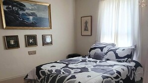 A bedroom with a bed, a painting, and a framed picture on the wall. - Our cozy apartment is your home away from home. 
 (Hibbing)