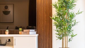 A reception desk with a potted bamboo plant, a bookshelf with books, and a framed artwork on the wall. - 2bed Chic Apt Burj Khalifa Gym/pool by Belvilla (Dubai)