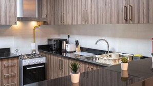 A modern kitchen with wooden cabinets, a stainless steel range hood, a gas stove, a built-in oven, a sink, and a dishwasher. - 2bed Chic Apt Burj Khalifa Gym/pool by Belvilla (Dubai)