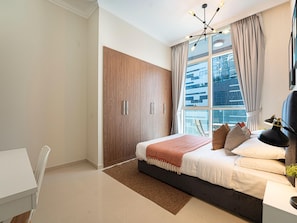 A modern bedroom with a large bed, a desk, and a wardrobe.