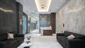 A modern lobby with dark sofas, a marble floor, and a reception desk.