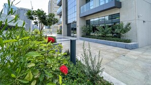 A modern building with a glass facade, surrounded by well-maintained greenery and a paved walkway.