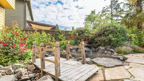 Une terrasse en bois avec une rambarde en métal, entourée de rochers et de plantes.