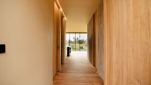 A modern hallway with wooden walls and a wooden floor, leading to a balcony with a view of palm trees. - Hygge Villa Ubud (Ubud)