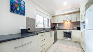 Een moderne keuken met witte kasten, een zwart aanrecht en een roestvrijstalen oven.
