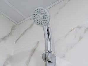 A chrome showerhead with a circular design and multiple holes, mounted on a wall with a marble-like texture. - 4bed Apt Dubai Marina Near JBR Pool by Belvilla (Dubai)