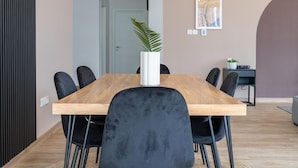 A modern dining area with a wooden table and black chairs, a potted plant, and a framed artwork on the wall. - 4bed Apt Dubai Marina Near JBR Pool by Belvilla (Dubai)