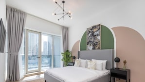 A modern bedroom with a large bed, a city view through floor-to-ceiling windows, and a unique ceiling light fixture. - 4bed Apt Dubai Marina Near JBR Pool by Belvilla (Dubai)