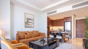 A modern living room with a sofa, a coffee table, and a dining area with chairs and a table. - Lux 1BR Apt Burj Khalifa View by Belvilla (Dubai)
