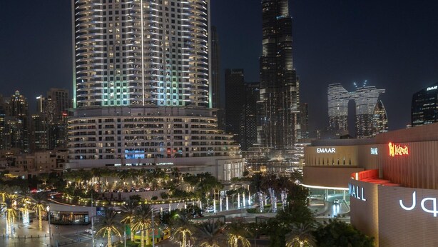 A cityscape with high-rise buildings, a shopping mall, and a well-lit street with palm trees. - Lux 1BR Apt Burj Khalifa View by Belvilla (Dubai)