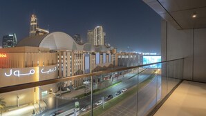 A modern building with a glass facade overlooking a busy road and city skyline at night. - Lux 1BR Apt Burj Khalifa View by Belvilla (Dubai)