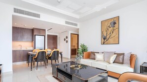 A modern living room with a sofa, coffee table, and dining area. - 1BR Dlx City View Near Dubai Mall by Belvilla (Dubai)