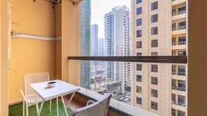 A balcony with a white table and two chairs, a view of high-rise buildings, and a clear sky.