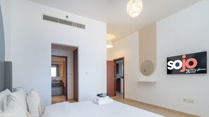 Una habitación de hotel moderna con una cama grande, un baño visible a través de una puerta abierta y un cartel que dice 'sojo' en la pared.