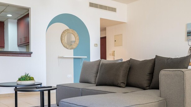 Una sala moderna con un sofá modular, una mesita redonda y una planta en maceta.