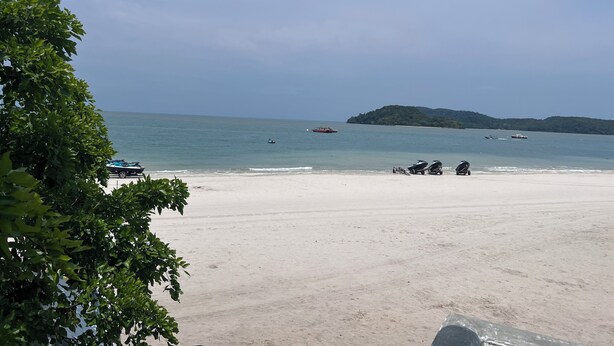 A beach with a clear sky, calm sea, and a distant island. - OYO 90981 Chenang Rest House 1 (Langkawi)