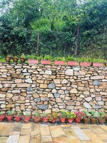 Una pared de piedra con plantas en macetas dispuestas a lo largo de los bordes superior e inferior.