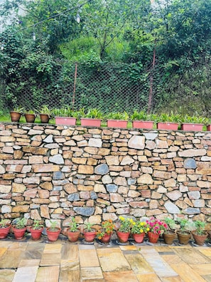 A stone wall with potted plants arranged along its top and bottom edges.