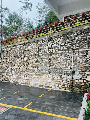 A stone wall with a metal railing and potted plants. - Pine Tree Resort (Baluwapati Deupur)