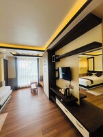 Quarto de hotel com cama, televisão, escrivaninha e cadeira.