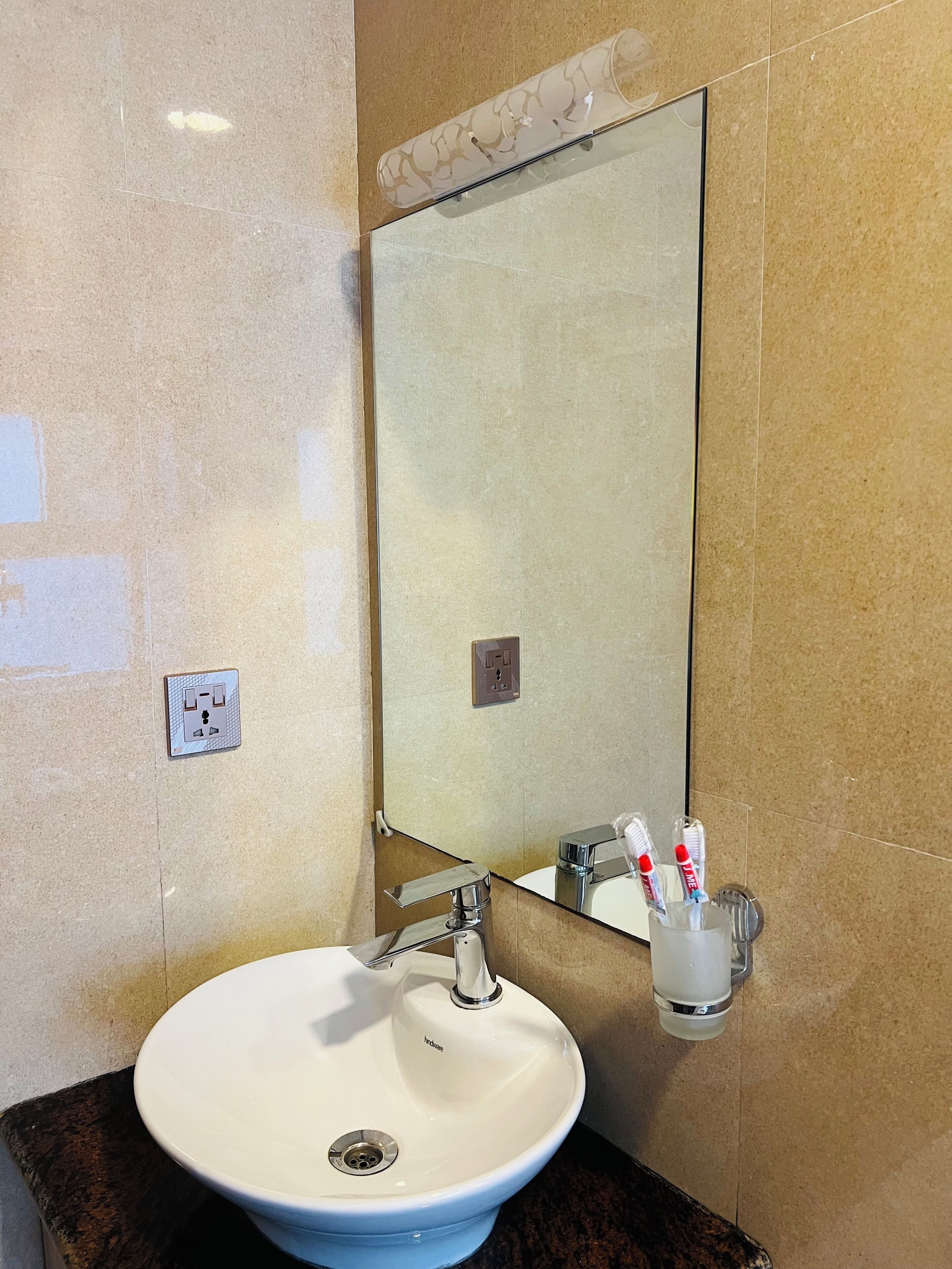 A bathroom with a white sink, a mirror, and a wall-mounted toothbrush holder.