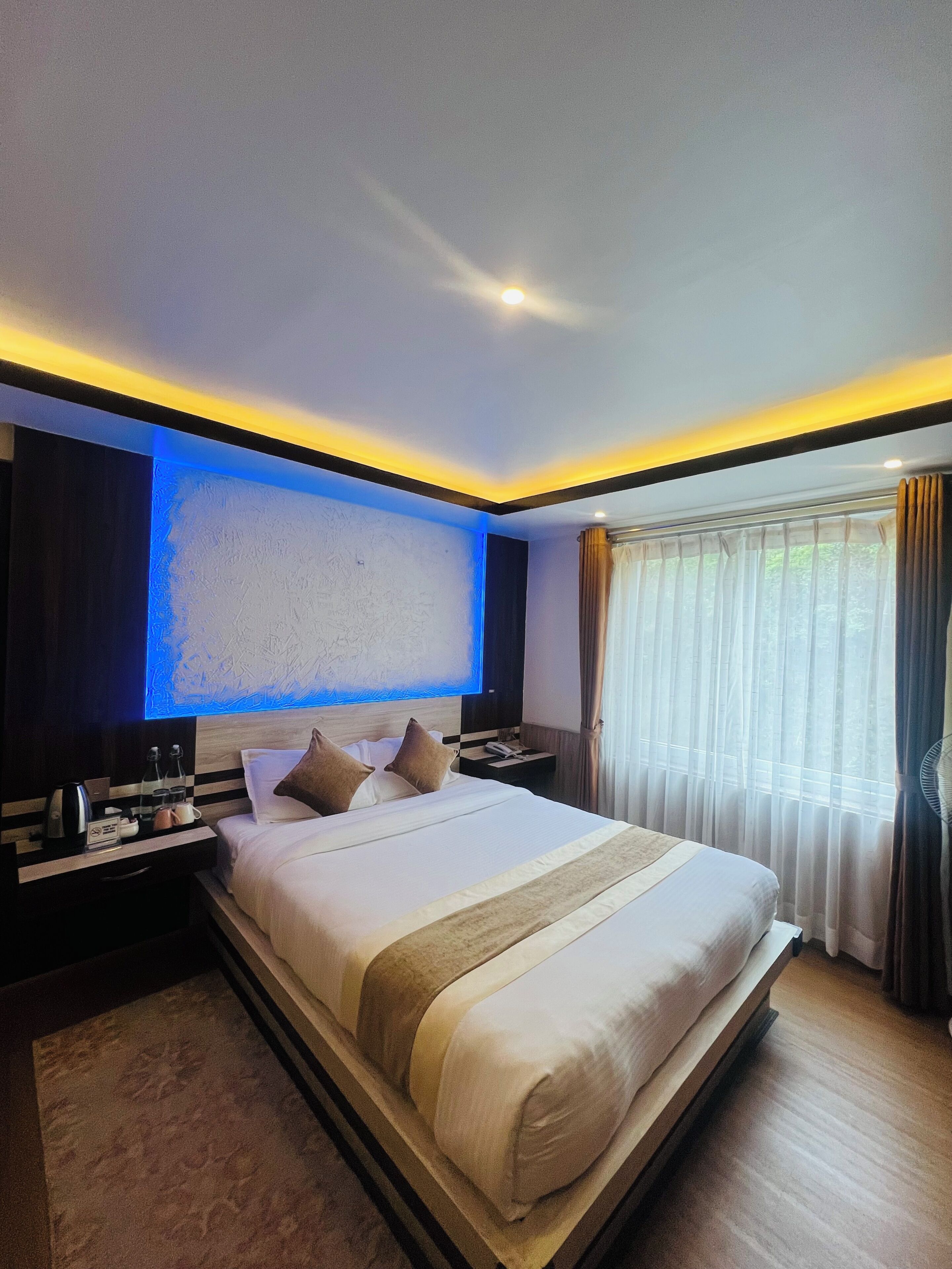 Quarto de hotel com uma cama grande, mesas de cabeceira, televisão de tela plana e uma janela com cortinas.