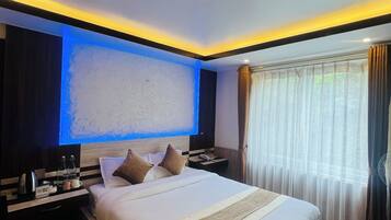 Quarto de hotel com uma cama grande, mesas de cabeceira, televisão de tela plana e uma janela com cortinas.