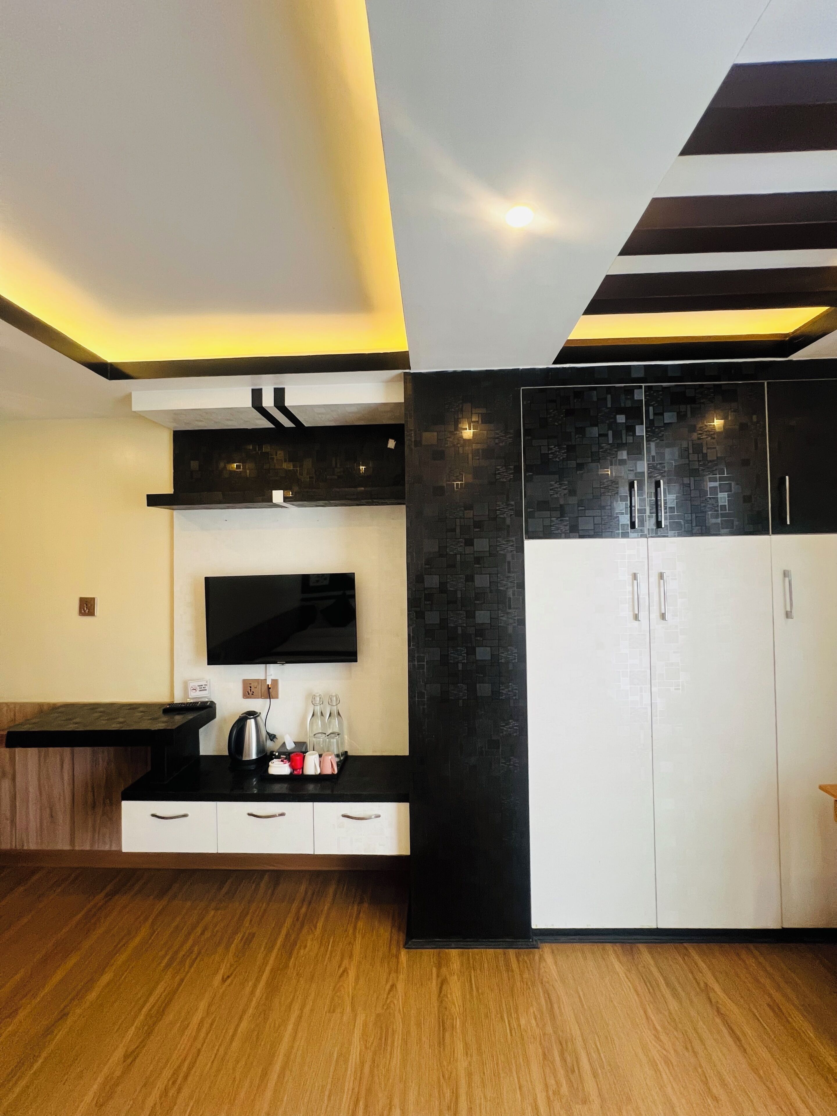 A modern kitchen with a built-in TV, a black countertop, and a wooden floor.