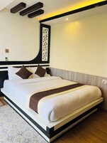 Una habitación de hotel moderna con una cama grande, un panel decorativo en la pared y un estante empotrado.