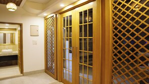 A hotel room with wooden doors, a bathroom with a sink, and a lattice partition. - Grand Vistana (Dhaka)