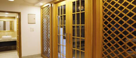 A hotel room with wooden doors, a bathroom with a sink, and a lattice partition.