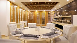 A conference room with a round table set for a meeting, surrounded by white upholstered chairs. - Grand Vistana (Dhaka)