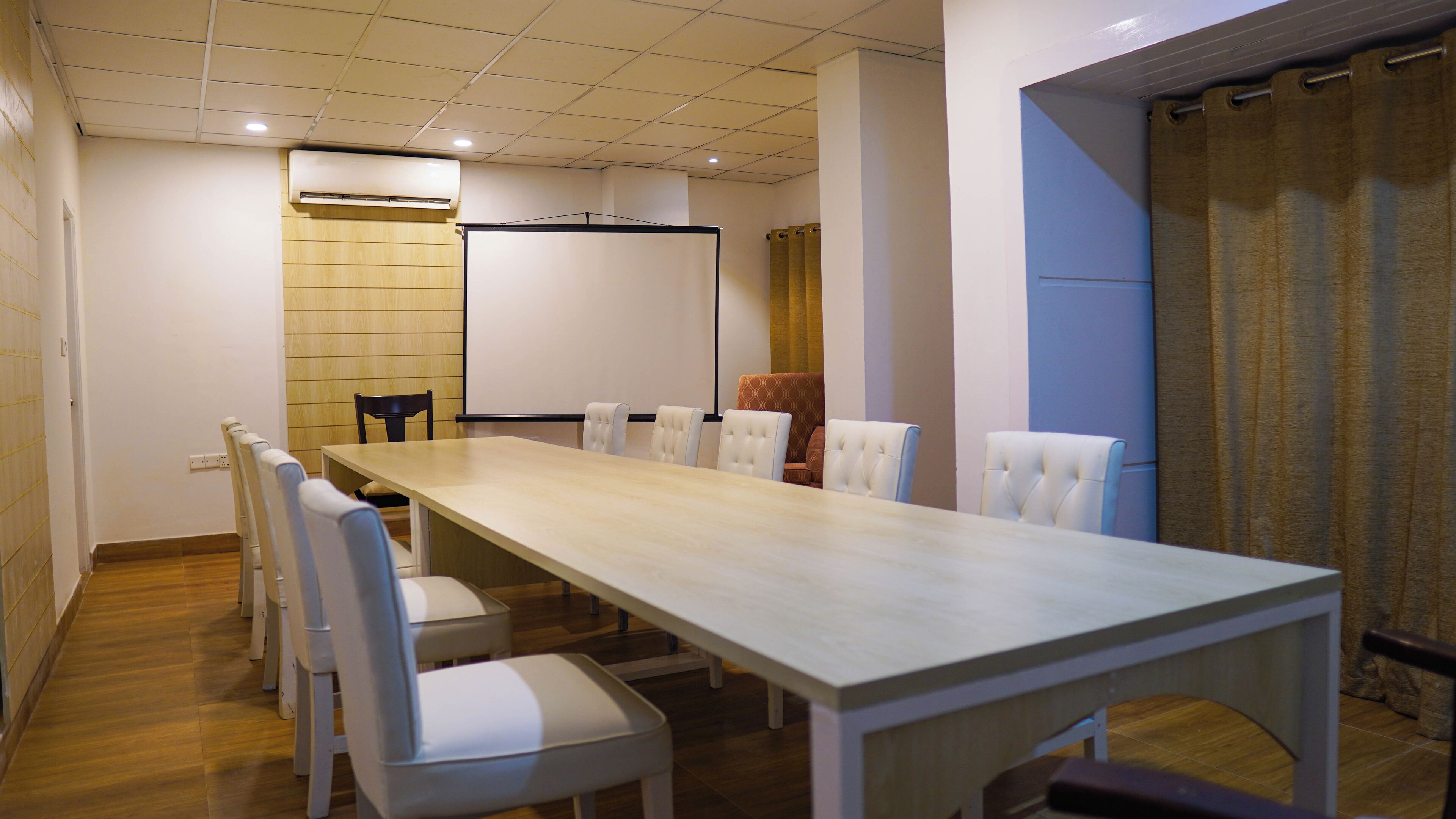 Une salle de conférence équipée d’une longue table, de plusieurs chaises, d’un tableau blanc et d’un appareil de climatisation.