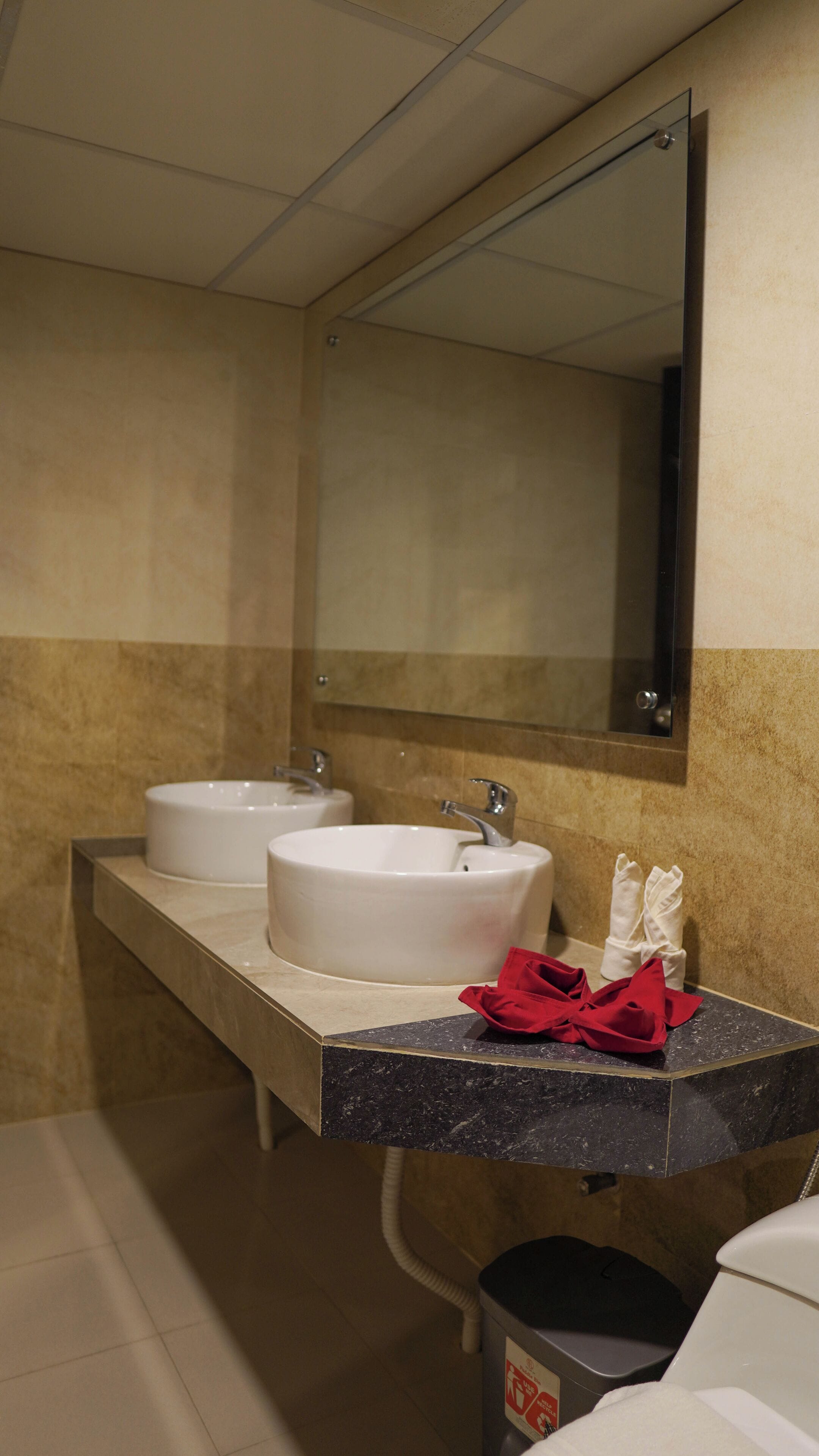 A bathroom with two sinks, a mirror, and a trash can.