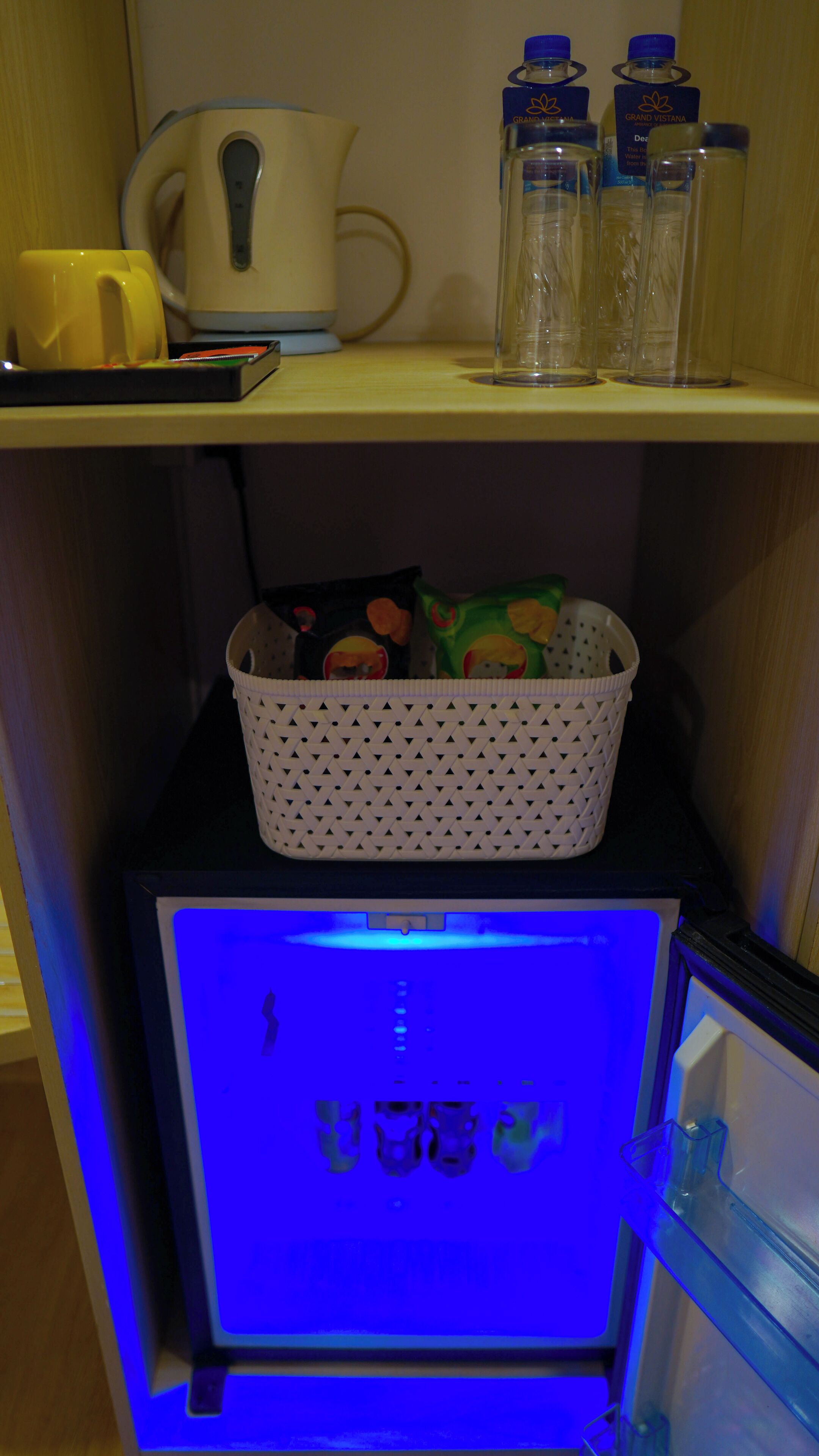 Un coin cuisine équipé d’un réfrigérateur, d’un four à micro-ondes et d’un panier contenant divers articles.