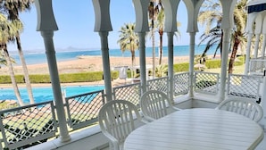 A covered outdoor seating area with a pool view, white chairs, and a table. - Beautiful and comfortable apartment  with communal pool in Denia, Costa Blanca, Spain for 4 persons (Denia)