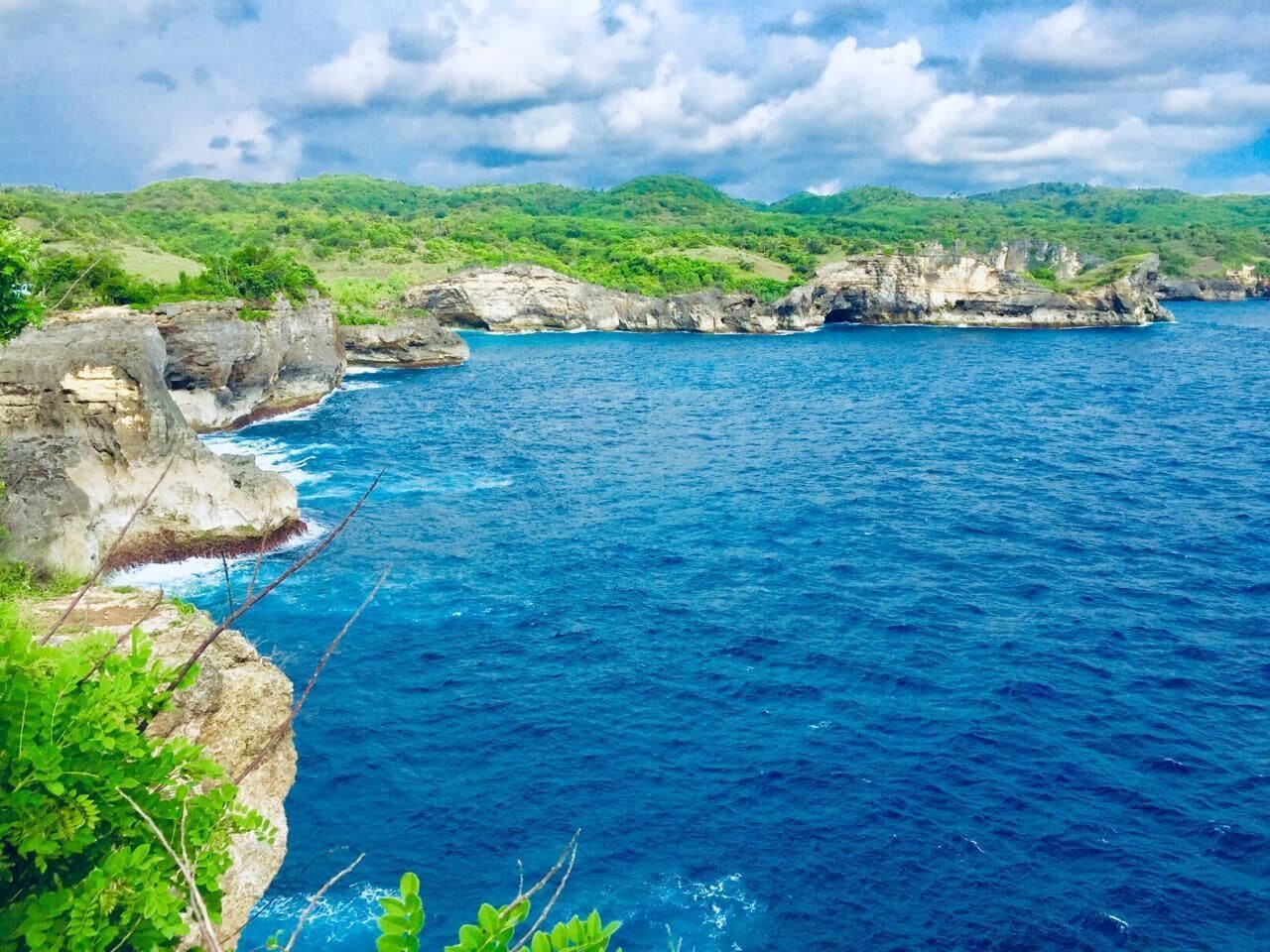 A coastal landscape with rocky cliffs and a clear blue sea.